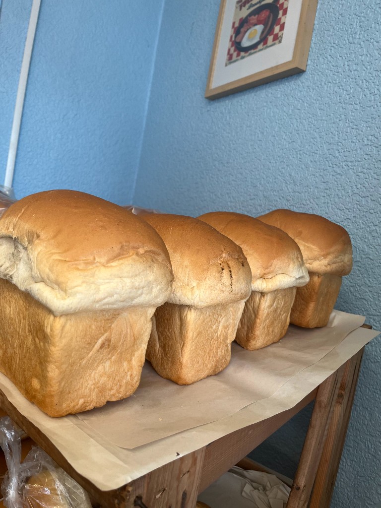 Fresh white loaves on the shelf with a full English breakfast picture on the wall