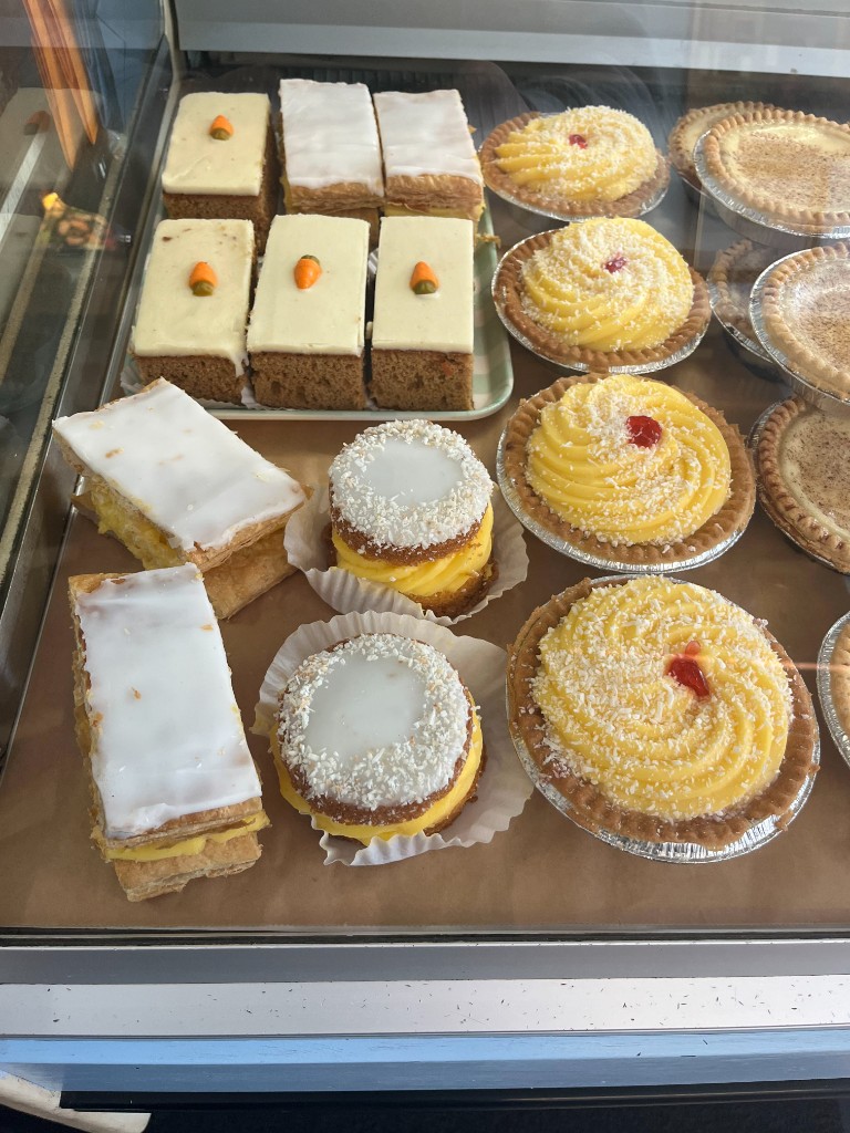 Handmade cakes and pastries in the chilled display: carrot cake, vanilla slices, coconut tarts and more